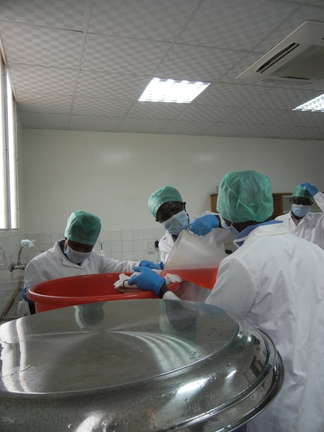 Adding the batch of concentrated morphine with the dye added (see it looks pink) to the full container to make the correct dilution.