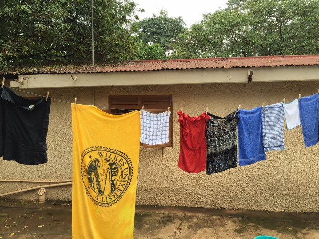 Hanging laundry to dry. My house is in the background. The blue wash bucket is on the cement.